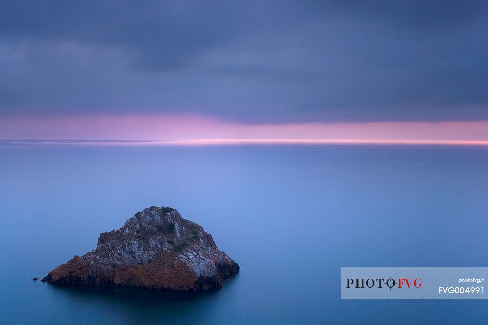 The Scoglo of the Dead is a cliff that rises from the sea just off the south west coast of Sardinia. Here it is taken at sunset, Nebida, Sulcis-Iglesiente, Sardinia, Italy