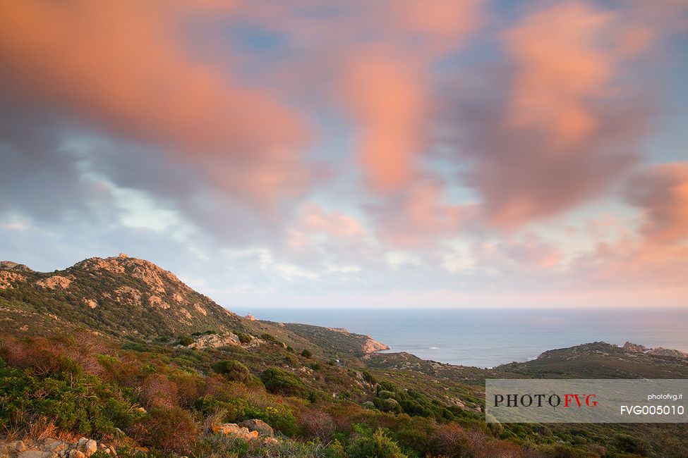 The lighthouse at Cape Teulada taken from an unusual angle, and the coast that is still wild and covered by the typical Mediterranean vegetations, Chia, Domus de Maria, Sulcis-Iglesiente, Sardinia, Italy