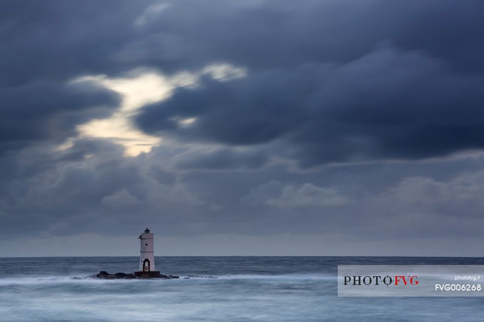 The famous small lighthouse of Mangiabarche (Calasetta) during a little winter storm 