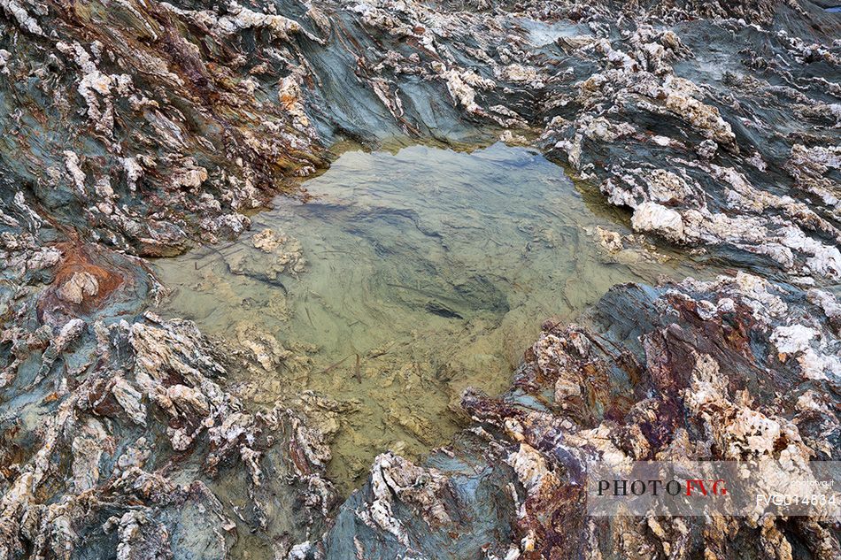 The colors of the rocks of the Piscinn bay appear lit from the sun on the horizon, giving unusual and attractive colors, Piscinn, Sulcis-Iglesiente, Sardinia, Italy