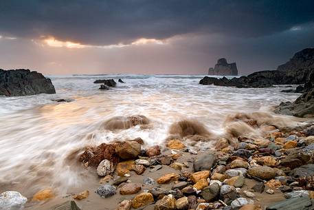 Sea storm in a gray winter day in Masua. In the background the stack of Sea storm in a gray winter day in Masua. In the background the stack of