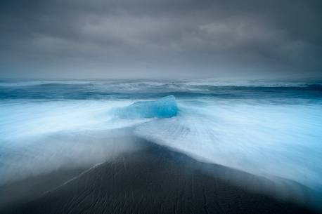 Lonely iceberg on the black sand beach near Jokulsarlon glacier lagoon, Iceland