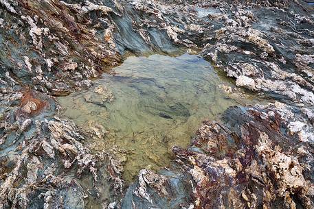 The colors of the rocks of the Piscinně bay appear lit from the sun on the horizon, giving unusual and attractive colors, Piscinně, Sulcis-Iglesiente, Sardinia, Italy The colors of the rocks of the Piscinně bay appear lit from the sun on the horizon, giving unusual and attractive colors, Piscinně, Sulcis-Iglesiente, Sardinia, Italy