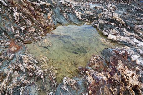 The colors of the rocks of the Piscinn bay appear lit from the sun on the horizon, giving unusual and attractive colors, Piscinn, Sulcis-Iglesiente, Sardinia, Italy