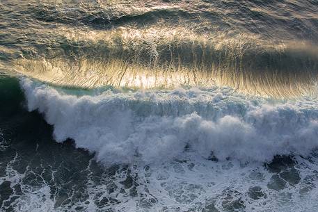 The sun at sunset, illuminates the waves crashing against the cliffs of Capo Nieddu The sun at sunset, illuminates the waves crashing against the cliffs of Capo Nieddu