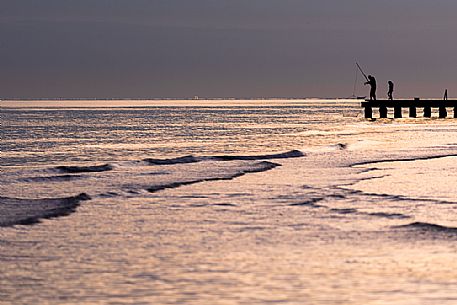 Fisherman on the dock at sunset, Lido di Jesolo, Venice, Italy.