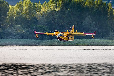 Firefighting airplane, Bombardier 415 - Canadair CL-415, taking water from the Lake, Somplago, Cavazzo Carnico, Udine, Italy. Firefighting airplane, Bombardier 415 - Canadair CL-415, taking water from the Lake, Somplago, Cavazzo Carnico, Udine, Italy.