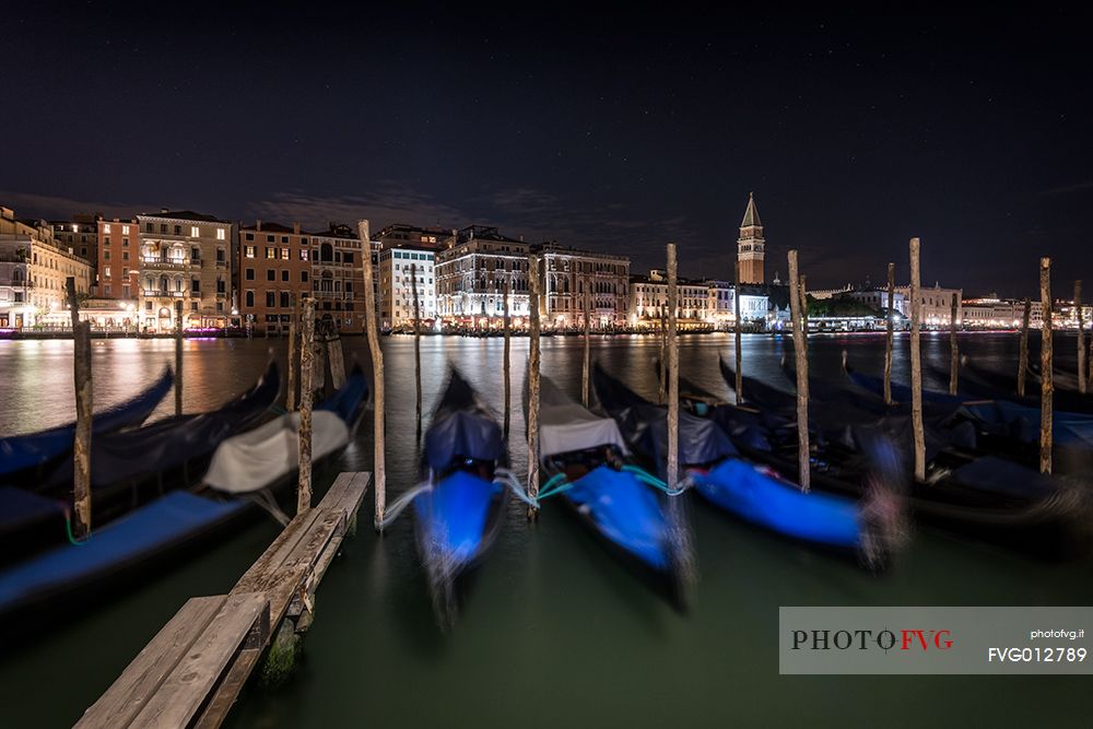 Gondolas moored by night, in the background the Campanile San Marco bell tower and the historical palaces of Venice, Venice, Veneto, Italy, Europe