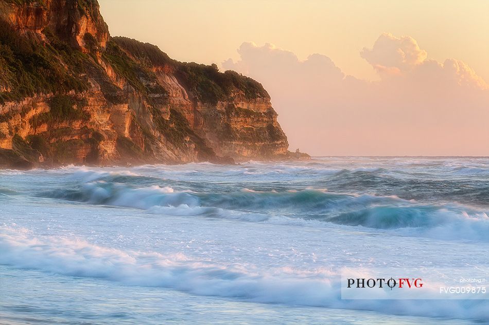 The symphony of the waves and the golden light of sunset in the Bay Statues in Santa Sunday fall during a violent storm