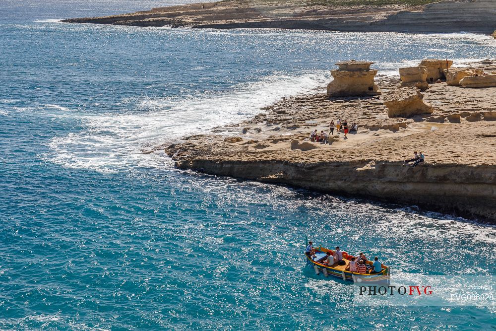 Trip with Iuzzu boat in the sea of St. Peter's Pool, one of the most beautiful natural pools near Marsaxlokk on the island of Malta, Europe