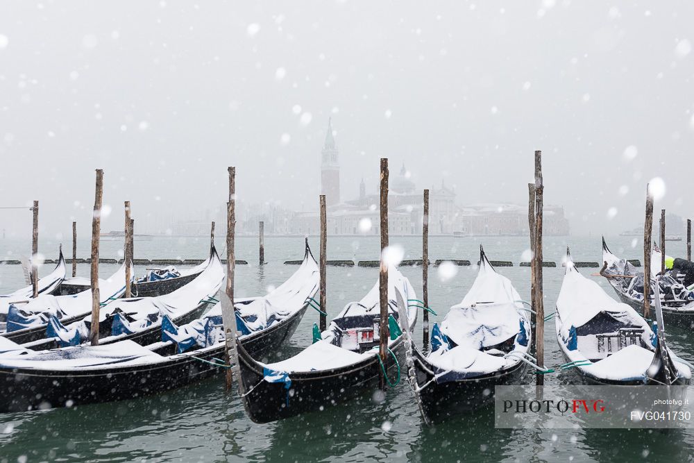 Winter snowfall in the city of Venice, gondolas covered by snow and in the background the San Giorgio Maggiore church, Venice, Veneto, Italy, Europe