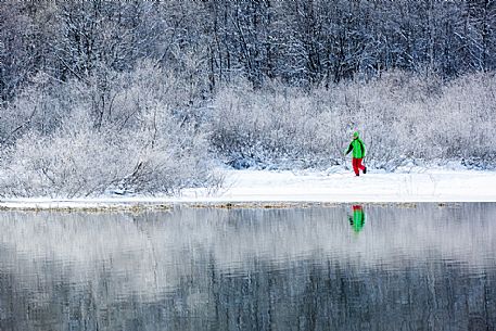 Hiker at Fusine lake in a winter landscape, Tarvisio, Julian Alps, Italy Hiker at Fusine lake in a winter landscape, Tarvisio, Julian Alps, Italy