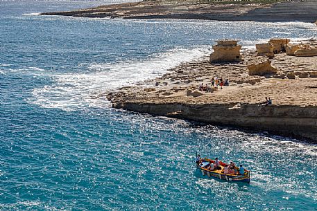 Trip with Iuzzu boat in the sea of St. Peter's Pool, one of the most beautiful natural pools near Marsaxlokk on the island of Malta, Europe