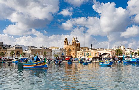 The historic city of Marsaxlokk on the island of Malta, famous for its colorful fishing boats called Iuzzu, in the background the Parish church dedicated to Our Lady of Pompeii, Malta, Europe The historic city of Marsaxlokk on the island of Malta, famous for its colorful fishing boats called Iuzzu, in the background the Parish church dedicated to Our Lady of Pompeii, Malta, Europe