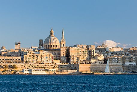 Panoramic view of Saint Paul's Cathedral and the ancient walls of Valletta with sail boat at the sunset, Malta, Europe