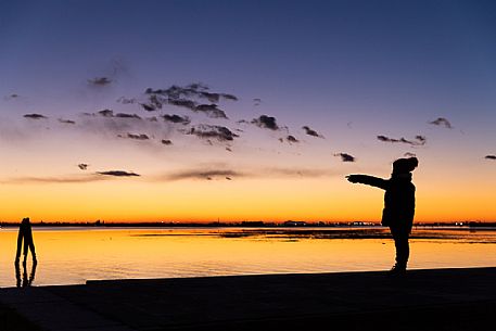 Child in silhouette at twilight with Venice in the background, from Burano island, Venetian lagoon, Veneto, Italy, Europe