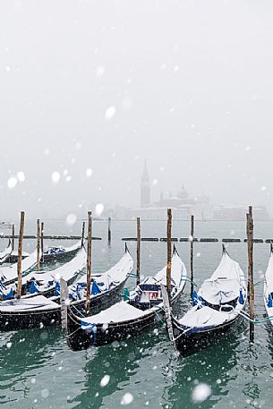 Winter snowfall in the city of Venice, gondolas covered by snow and in the background the San Giorgio Maggiore church, Venice, Veneto, Italy, Europe