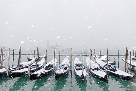 Winter snowfall in the city of Venice, gondolas covered by snow and in the background the San Giorgio Maggiore church, Venice, Veneto, Italy, Europe