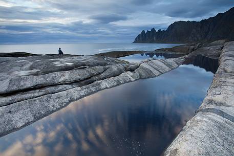 Admiring the beautiful landscape of Tungeneset, on Senja Island. In the foreground the famous Devil's Teeth. Admiring the beautiful landscape of Tungeneset, on Senja Island. In the foreground the famous Devil's Teeth.
