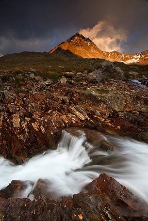 Mountain peak and river at sunset, Stelvio National Park, italian Alps.