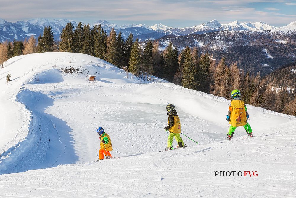 Three little children at the ski lesson in the piste of Biospharenpakbahn Brunnach, Nockberge mountain area, Bad Kleinkirchheim, Carinthia, Austria, Europe