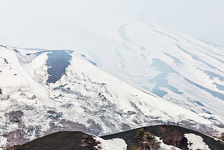 Tourists walking in foggy morning, in the background the Etna volcano from Sartorius mountais, Sicily, Italia