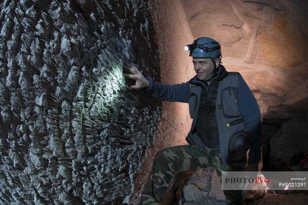 Person looks the wall worked by the miners' chisels in an old slate mine in Lavagna site, Liguria, Italy