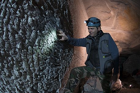 Person looks the wall worked by the miners' chisels in an old slate mine in Lavagna site, Liguria, Italy