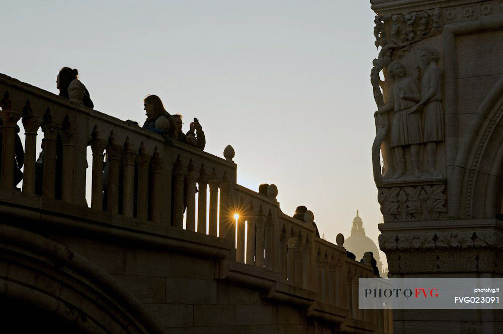 Tourists admire the ducal palace Palazo Ducale from the Straw bridge in Venice, in the distance the dome of the basilica di Santa Maria della Salute. Italy