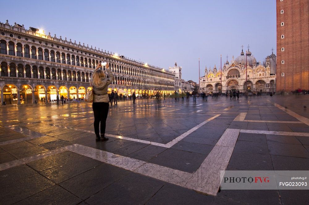 Tourist photographs the Basilica of St. Mark in Venice at twilight, Italy