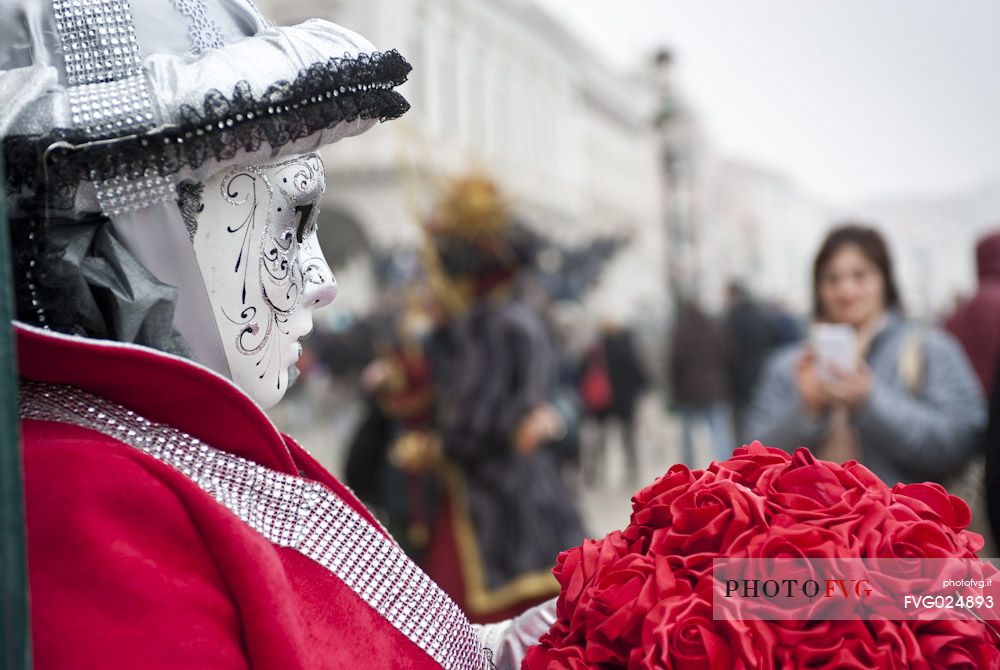 A tourist takes a picture of a colored mask in Saint Mark Square in Venice. Italy