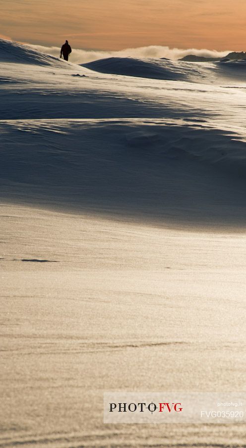 A solitary man walks in a snowy landscape in the Veneto Dolomites, Belluno, Italy