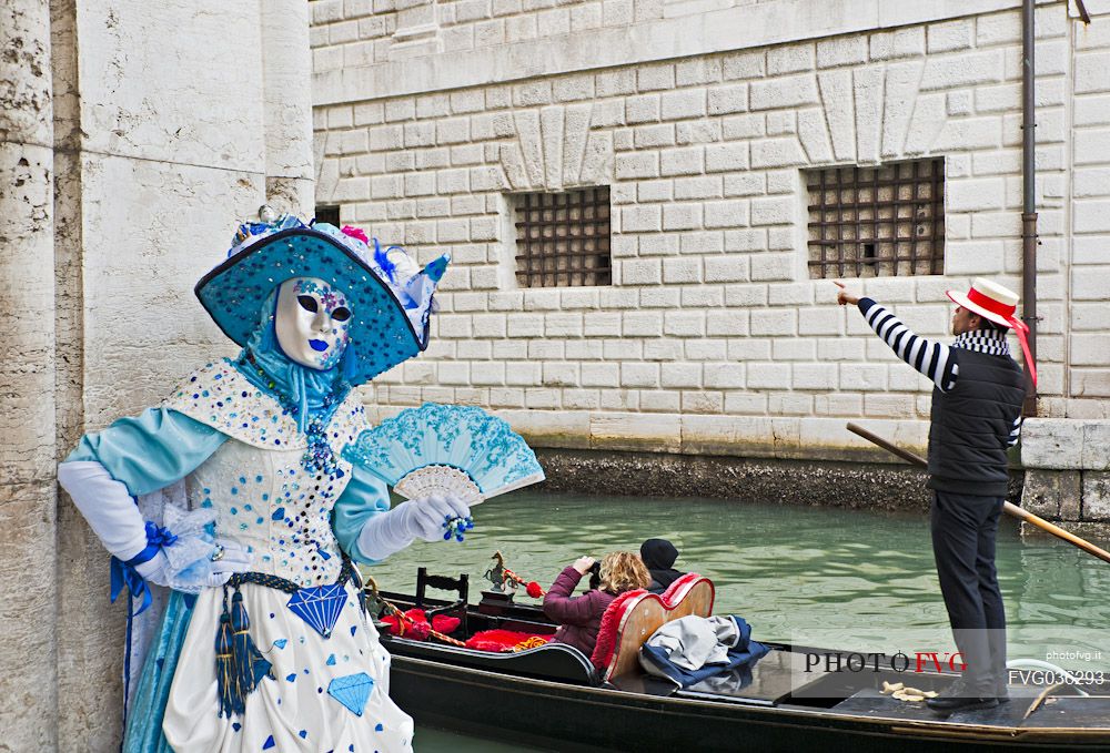 Mask and tourists in gondola near the Bridge of Sighs or Ponte dei Sospiri during the carnival in Venice, Italy, Europe