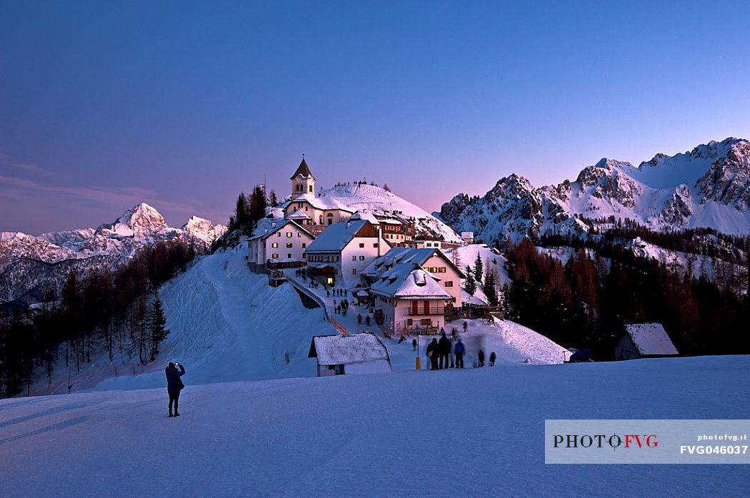 Tourists at the iconic village of Monte Lussari mount in a winter sunset, Tarvisio, Julian Alps, Friuli Venezia Giulia, Italy, Europe