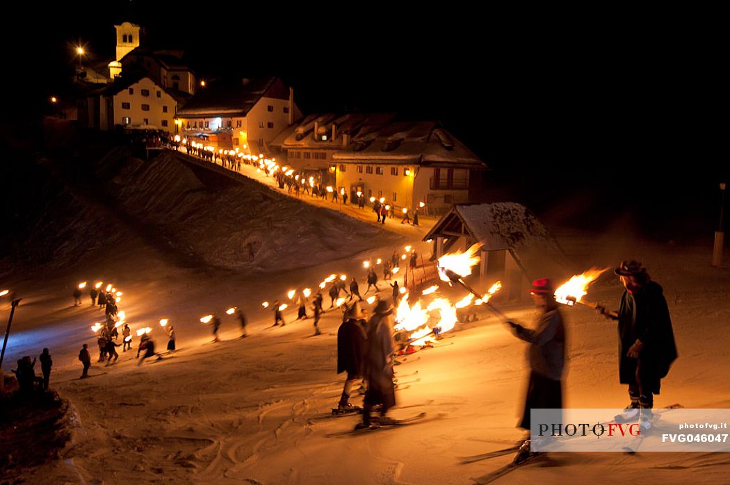 Costumed skiers descend from Monte Lussari mount with the torch lit on New Year's day. Tarvisio, Julian alps, Friuli Venezia Giulia, Italy, Europe
