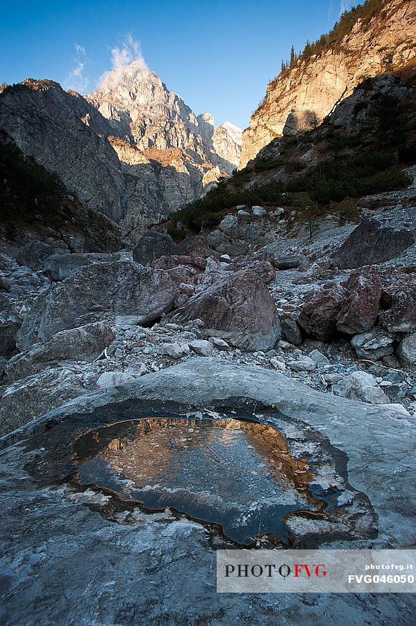 Monte Castello in the Friulian Dolomites natural Park is reflected in a pool of frozen water, Friuli Venezia Giulia, Italy, Europe