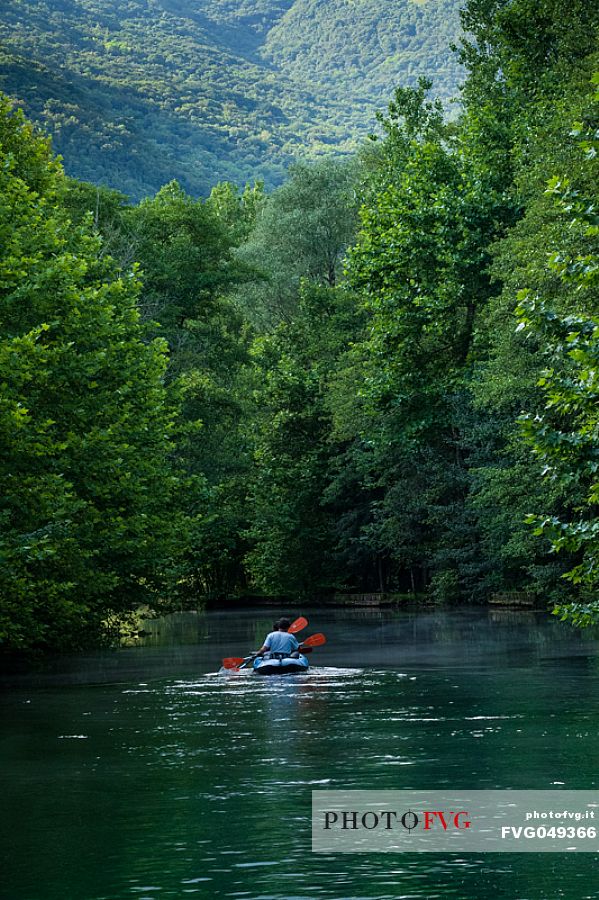 Tourists in canoes enjoy the panorama of the Livenza river near the source called 