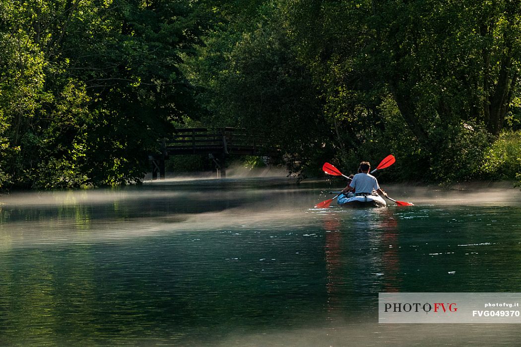 Tourists in canoes enjoy the panorama of the Livenza river near the source called 