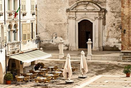 Man is reading the newspaper. Piazza del Popolo, in the background the entrance of the Cathedral of San Vito al Tagliamento, Friuli Venezia Giulia, Italy, Europe Man is reading the newspaper. Piazza del Popolo, in the background the entrance of the Cathedral of San Vito al Tagliamento, Friuli Venezia Giulia, Italy, Europe