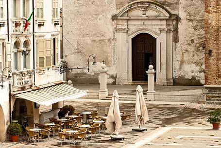 Man is reading the newspaper. Piazza del Popolo, in the background the entrance of the Cathedral of San Vito al Tagliamento, Friuli Venezia Giulia, Italy, Europe