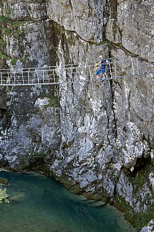 Father and son have fun on a suspension bridge in the park of the Friuli Dolomites above the river Cellina, Barcis, Friuli Venezia Giulia, Italy