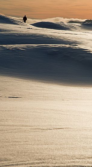 A solitary man walks in a snowy landscape in the Veneto Dolomites, Belluno, Italy