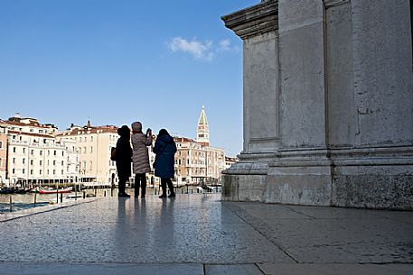Turists take pictures of the bell tower of San Marco from the churchyard of the Basilica of the Madonna della Salute in the Dorsoduro district of Venice, Italy, Europe Turists take pictures of the bell tower of San Marco from the churchyard of the Basilica of the Madonna della Salute in the Dorsoduro district of Venice, Italy, Europe