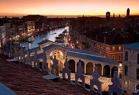 The famous Rialto bridge rises over the Grand Canal in Venice illuminated by the evening lights, Italy, Europe