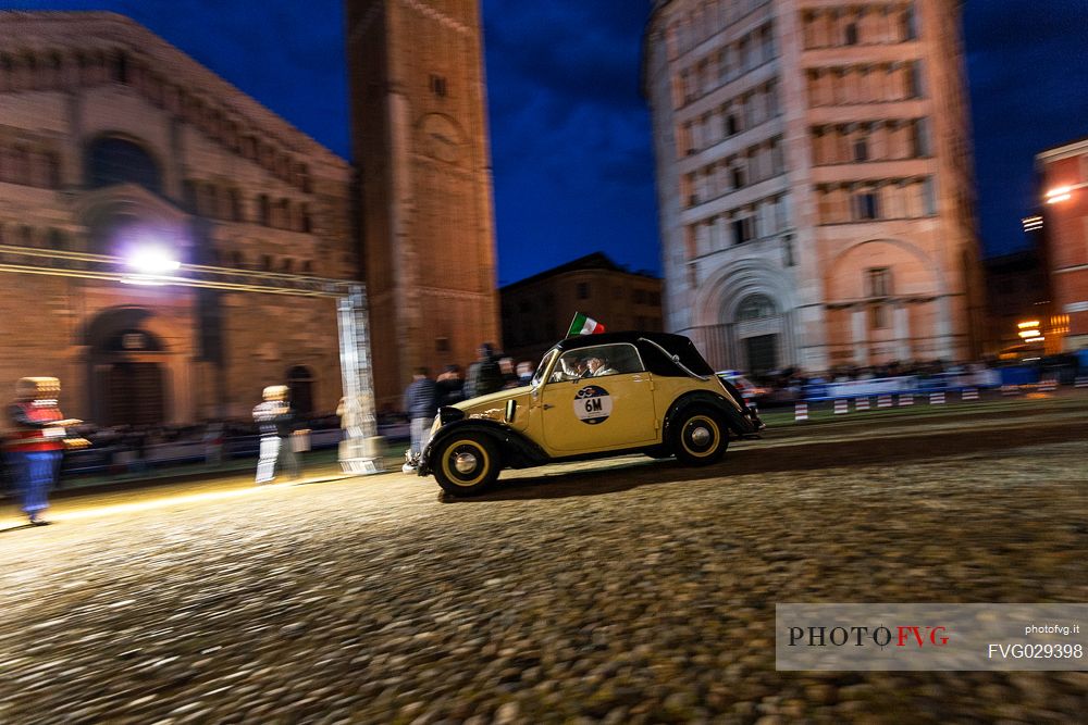 Vintage car race in the Piazza Duomo square with Baptistery and Cathedral, Parma, Italy