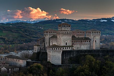 Torrechiara castle at twilight and in the background the Cusna mount, Langhirano, Emilia Romagna, Italy