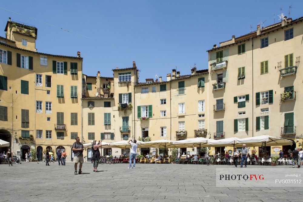 The picturesque Piazza Anfiteatro square in Lucca downtown, with its yellow houses and curved walls, Tuscany, Italy