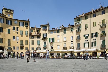 The picturesque Piazza Anfiteatro square in Lucca downtown, with its yellow houses and curved walls, Tuscany, Italy