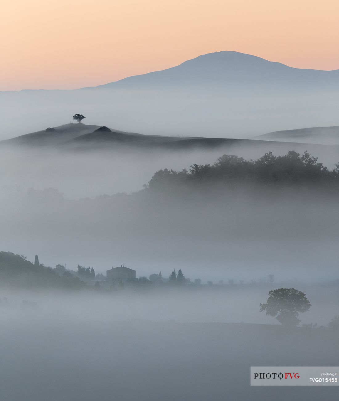 The fog of an autumn sunrise over the hills of Val D'Orcia