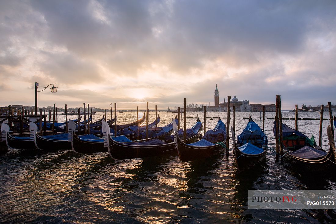 Venetian gondolas during a soft sunrise with the Basilica of St Giorgio Maggiore on background